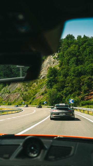 Vue depuis l'habitacle, une supercar en tête sur une route sinueuse